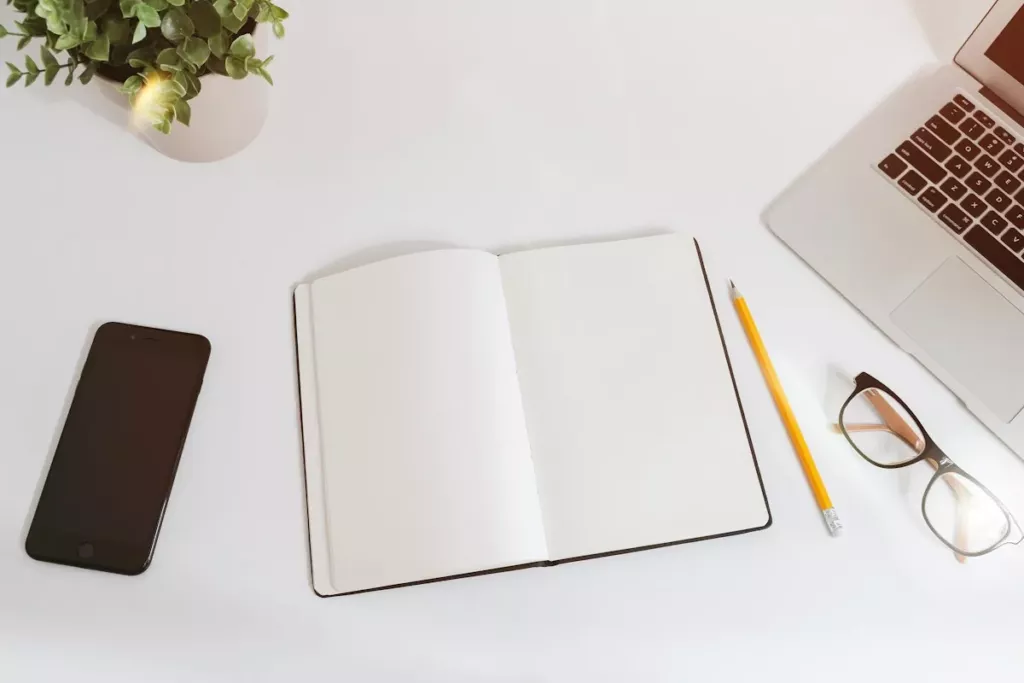 Carnet ouvert et stylo sur un bureau blanc, prêts pour noter ses priorités