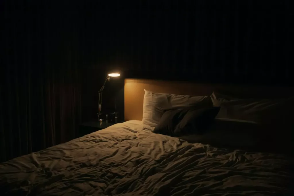 Chambre sombre éclairée par une petite lampe de chevet
