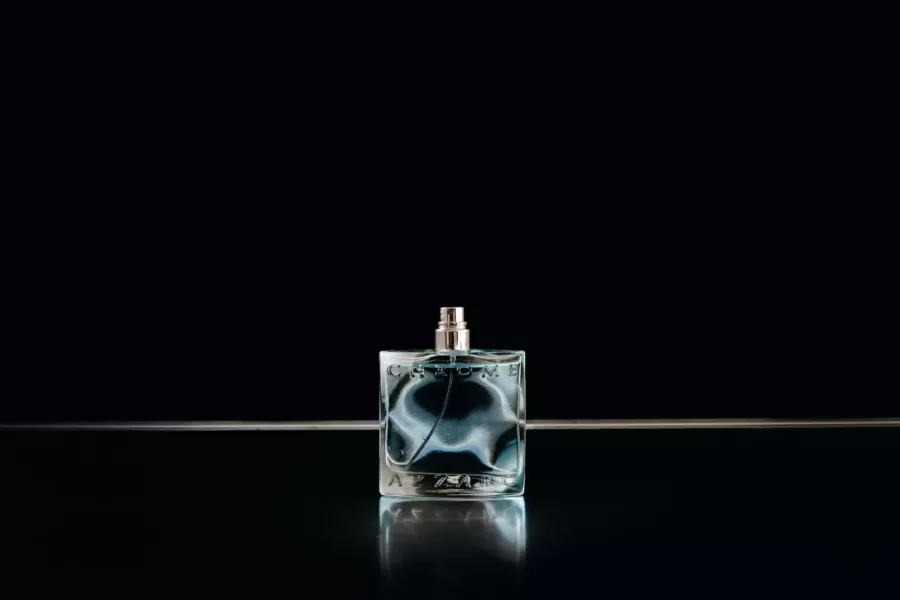 Flacon de parfum en verre sur fond noir, reflets argentés
