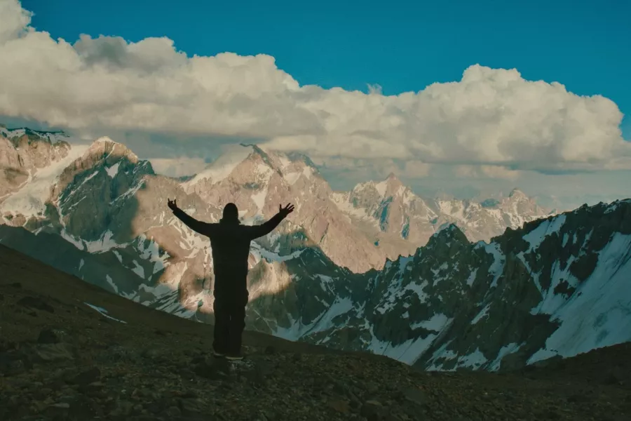 Homme les bras ouverts face aux montagnes enneigées