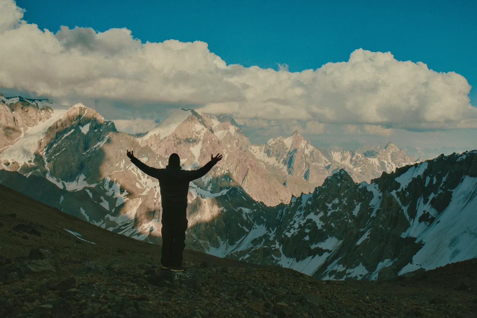 Homme les bras ouverts face aux montagnes enneigées