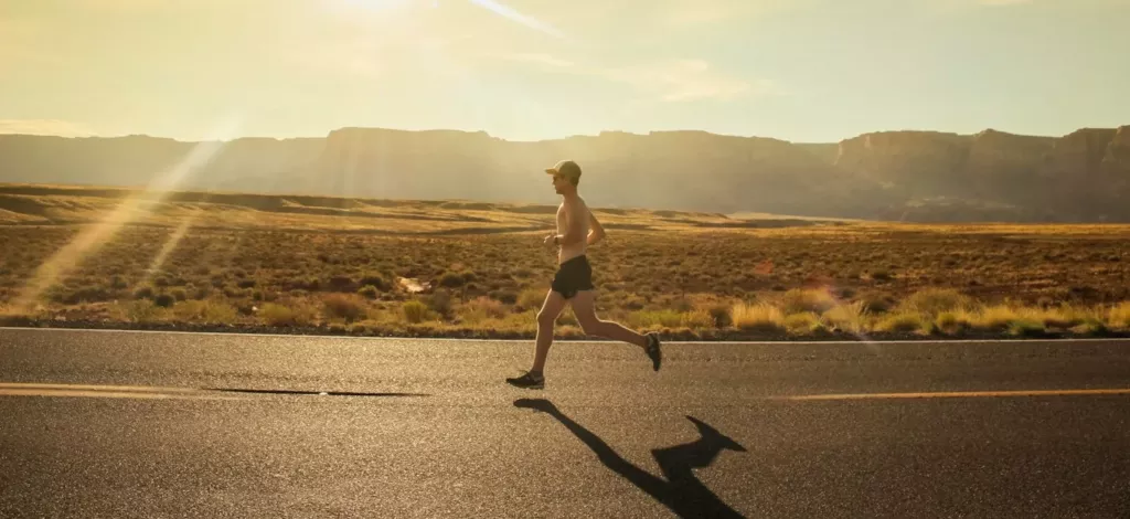 Homme qui court sur une route au soleil