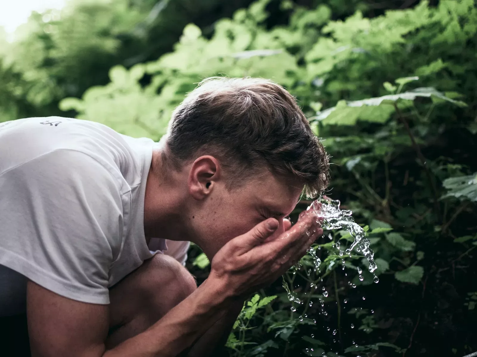 Homme qui se rince le visage à l’eau fraîche en plein air