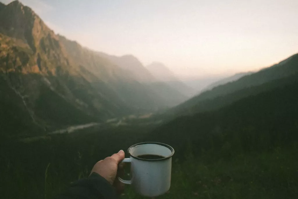 Tasse de café face à une vallée de montagne au petit matin