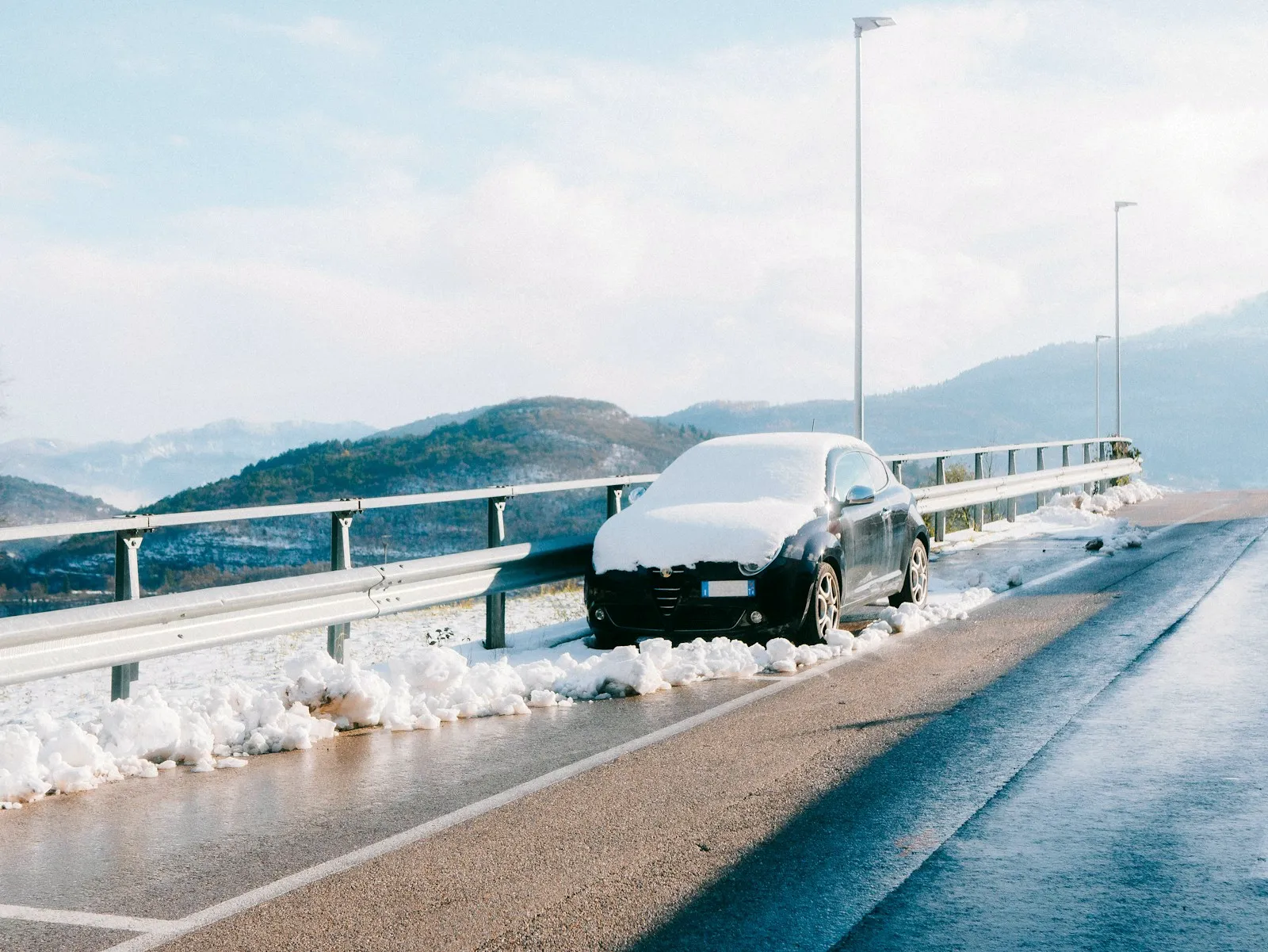 Voiture garée sur une route enneigée de montagne en hiver